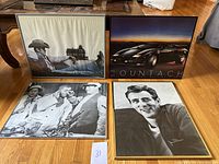 Four framed vintage posters laid on floor, including cowboy, Lamborghini Countach, classic black and white film scenes, and James Dean portrait.