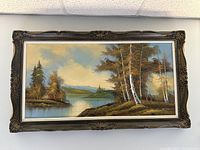 Full view of the framed oil painting showing a landscape of birch trees by a lake under a cloudy sky.