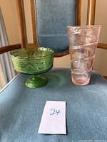 Green glass pedestal bowl and pink glass vase on blue chair