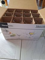 Top view of the box showing 12 clear stemmed wine glasses arranged in 3 rows and 4 columns, separated by cardboard dividers.