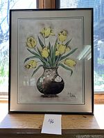 Photo of framed floral artwork showing yellow tulips in a vase, set by a window with natural light and clear view of artist signature.
