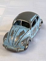 Front view of vintage blue and black Volkswagen die cast car with paint loss on hood and roof.