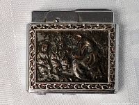 Front view of the metal pocket lighter with embossed human figures and ornate border.