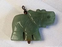 Front view of the carved green jade elephant pendant showing details and metal loop attachment.
