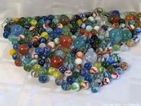 Wide top-down view of a large varied collection of marbles in assorted colors and patterns.