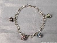 Full view of sterling silver chain bracelet with three jeweled spherical charms.