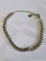Photo of the sterling silver thick chain bracelet laid flat on a cloth surface showing full length and clasp.