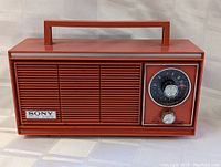 Front view of vintage orange SONY solid state 6 transistor radio with built-in handle and tuning and volume knobs