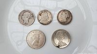 Front view of five silver coins showcasing the obverse sides with portraits including Queen Victoria and Queen Elizabeth II.