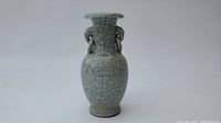 Front and full view showing crackle celadon glaze and bulbous vase shape with flared lip and ring handles.