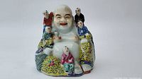 Front view of the Chinese porcelain seared Buddha with five boys figurine showing colorful clothing and joyful facial expressions.