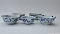 Front view of five blue and white Chinese porcelain bowls in varying sizes, arranged in a line showing decoration details.
