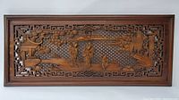 Full view of the rectangular wooden relief carving showing the entire scene and surrounding carved borders.