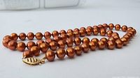 Close-up of the brown freshwater pearl necklace showing the high luster pearls and gold clasp.