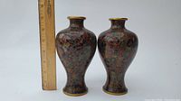 Pair of cloisonne vases shown with a ruler for size reference approximately 7 inches tall