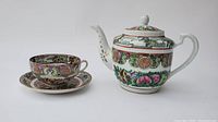Full view of teapot, cup, and saucer showing ornate Chinese style decoration and patterns.