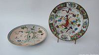 Two hand-painted Chinese porcelain plates side by side on a white background, showing full top views of the decorated surfaces.