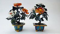 Two small jade trees with orange and white flowers in colorful cloisonné pots, front view.