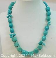 Full view of turquoise necklace on display bust showing bead shapes and silver spacers.