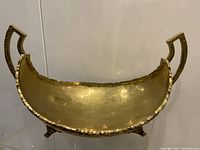 Front view of large vintage 1960s hand-hammered brass fruit bowl showing oval shape, scalloped edges and two decorative handles