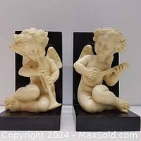 Pair of Bianchi bookends showing cream-colored cherubs playing flute and lute mounted on black bases.