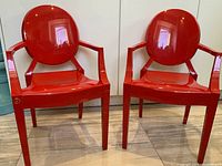 Front angled view of pair of red Philippe Starck Kartell Lou Lou chairs.