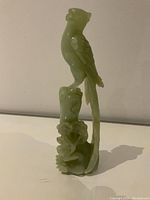 Front view of the carved jade bird figurine showing detailed carving and base.