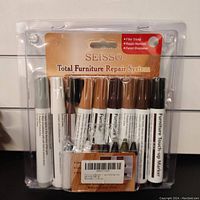 Front view of sealed Seisso Total Furniture Repair System kit with visible filler sticks, repair markers, and pencil sharpener in plastic packaging.