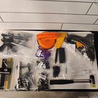 Overview photo of kit laid out, showing dent pullers, glue tabs, glue gun, spray bottle, hammer, and plastic tools all neatly displayed on a white floor.