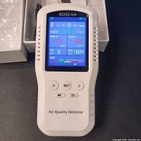 Front view of the Bosean air quality detector powered on displaying readings for HCHO, PM2.5, TVOC, CO, CO2, AQI, temperature, and humidity.