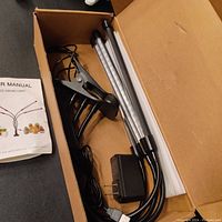 Full view of LED grow light set in box, includes 4 LED light bars with attached flexible goosenecks and a large clip base, plus power adapter and cable.