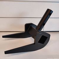 Close-up angled photo showing the solid steel pallet breaker part with two flat prongs and a cylindrical handle attachment, all powder coated black.