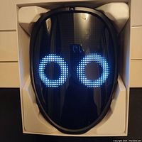 LED mask displaying two large blue circle eyes on the LED screen in its packaging.