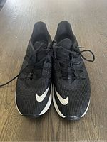 Top front view showing black mesh upper with white Nike swoosh on each shoe toe area and black laces tied.