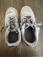 Top view showing grey Nike Air sneakers with visible signs of wear and dirt, grey laces tied loosely.