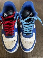 Front top view of Nike Air shoes showing mismatched red and blue laces and blue and white colorway.