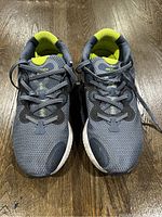 Top view photo of the pair of gray Nike running shoes with neon yellow interior, showing laces and shoe fronts on wooden floor.