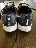 Rear view showing 'RUNNING' text and Nike swoosh on heel tab along with wear on soles.