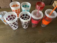 View of all plastic cups arranged showing different colors and styles including polka dot and tumblers with lids and straws.