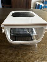 Front view of white vegetable chopper showing handle and top area with safety lock.