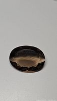 Top angle photo of the oval cut natural smokey quartz gemstone showing its transparency and brown shade.