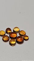 Photo showing 10 polished golden citrine cabochon gemstones with warm amber-yellow color and smooth rounded tops.