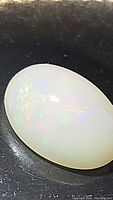 Close up of the oval natural Ethiopian opal cabochon showing light color play on milky base