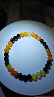 Top-down view of the natural gemstone bracelet arranged in a circle on a white background showing alternating patterns of black onyx and yellow agate beads.