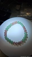 Photo of the natural green aventurine and strawberry quartz bead bracelet laid circularly with lighting highlighting the color and texture of the beads.