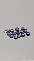 Several small natural purple iolite round cabochon gemstones displayed on a flat surface.