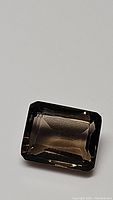 Rectangular emerald cut smokey quartz gemstone showing clarity and cut.