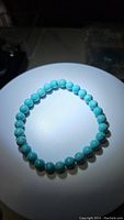 Turquoise bead bracelet laid flat on white surface, showing round robin's egg blue stones with slight natural pattern variations.