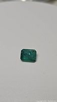 Front view of rectangular emerald cut natural emerald gemstone with visible inclusions.