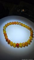 Yellow orange agate bead bracelet laid flat in a circular shape, showing bead colors and patterns under light.
